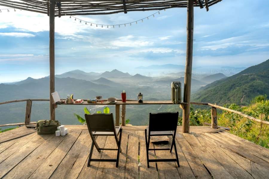 Une terrasse en bois rustique en altitude avec deux chaises face à un panorama montagneux pour entretenir ses terrasses en bois.