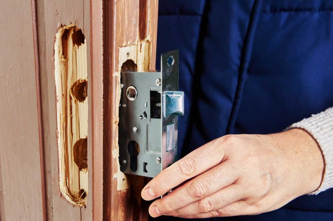 Un artisan installe le mécanisme d'une serrure encastrée en bois pour changer barillet de porte d entree serrurier paris.